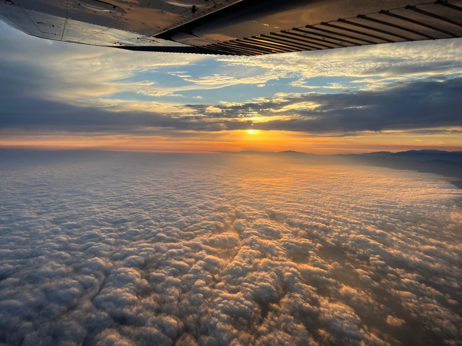 Sunset above the clouds from cockpit